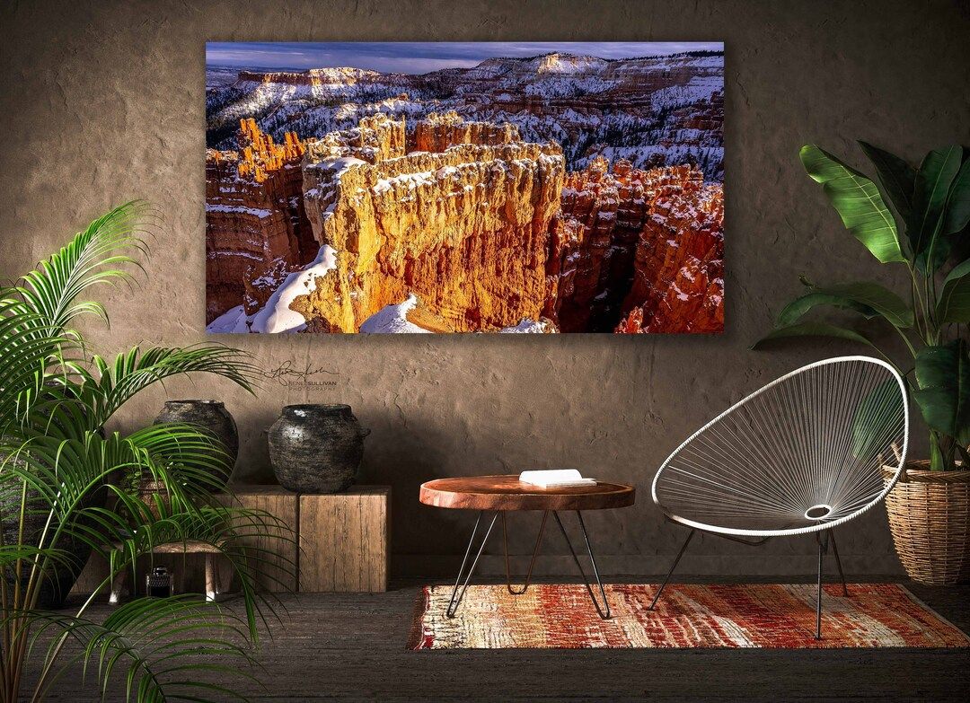 A large canvas print of Bryce Canyon hoodoos with snow hangs in a rustic interior.