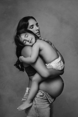 Black and white maternity photo showing tender moment between mother and sleeping child.
