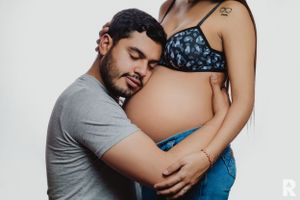 Intimate maternity portrait of couple embracing against studio backdrop.