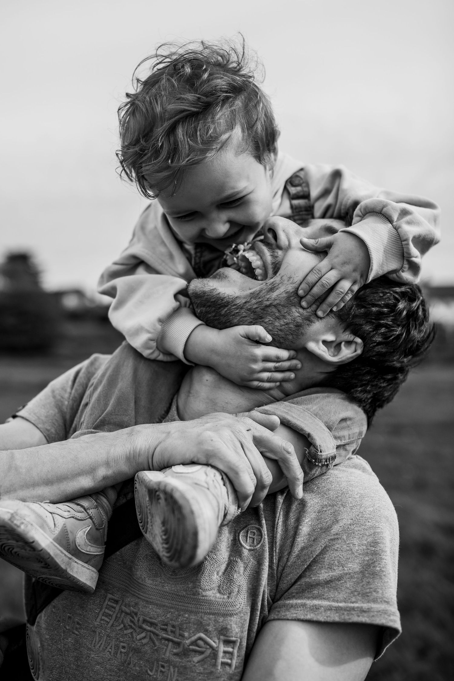 A joyful black and white portrait of playful interaction between parent and child outdoors.