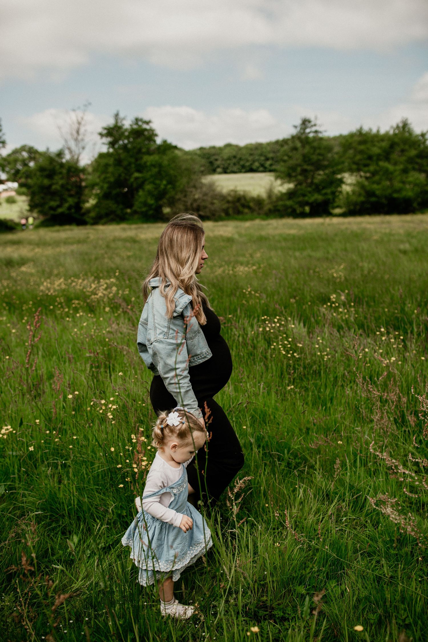 Mother and child standing in wildflower meadow wearing matching denim outfits. Essex Family lifestyle photoshoot in manningtree
