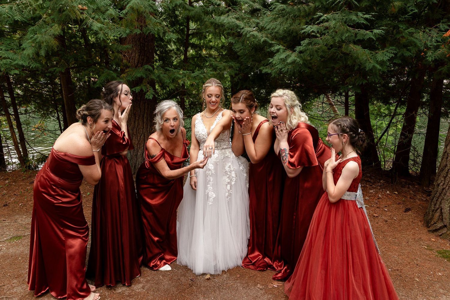 Bridesmaids in burgundy dresses react emotionally during a wedding moment.