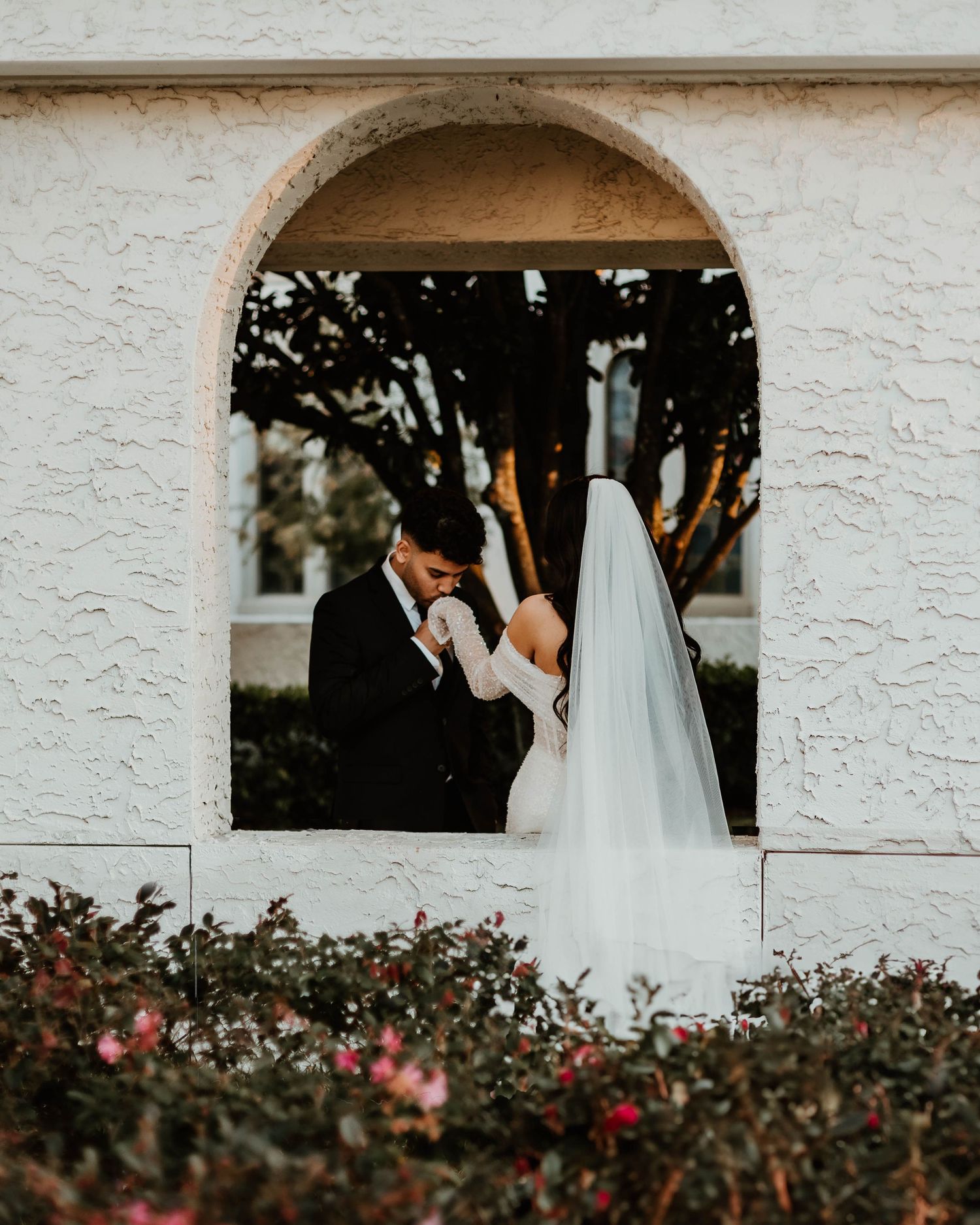 A romantic garden wedding ceremony under white arches with pink roses.