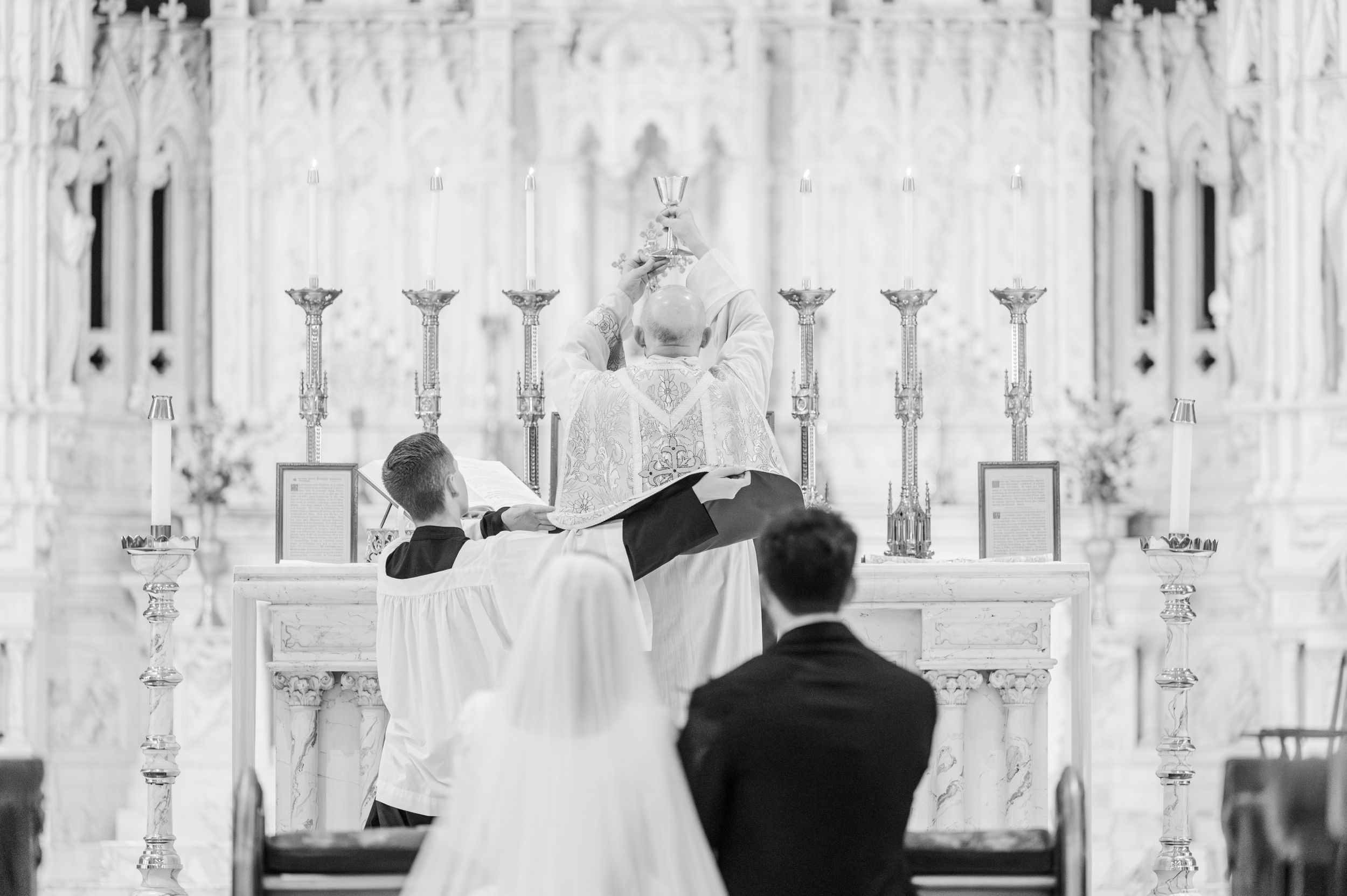 Priest elevates Host for Consecration at Catholic wedding at Holy Family Cathedral in Tulsa, OK.