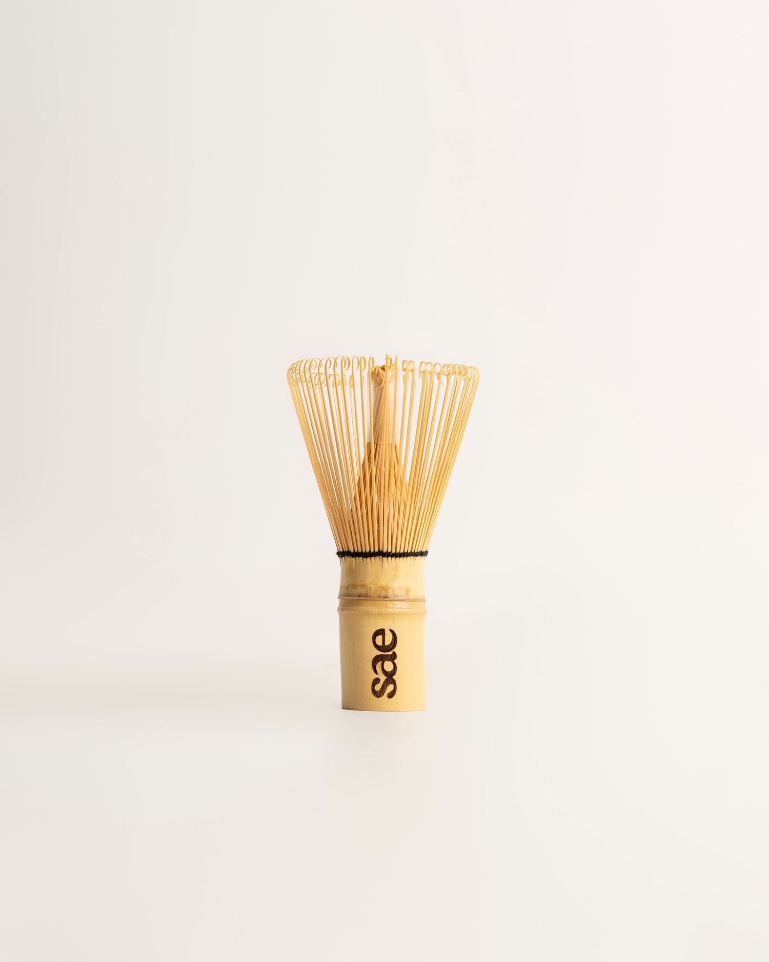 SAE branded bamboo matcha whisk with fine tines, perfect for preparing traditional Japanese matcha tea.