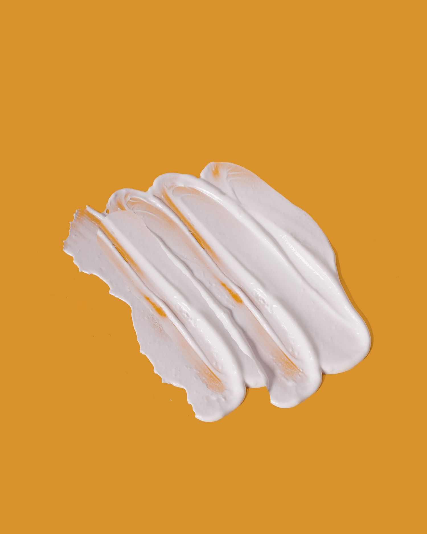 Abstract white paint strokes on orange background creating artistic texture.