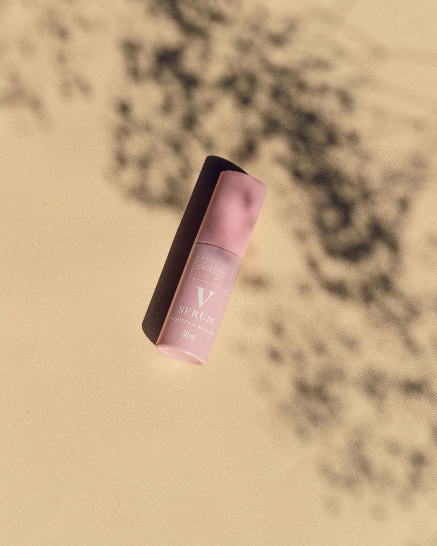 Pink cosmetic product stick casting shadows on beige background in minimalist beauty product photography.