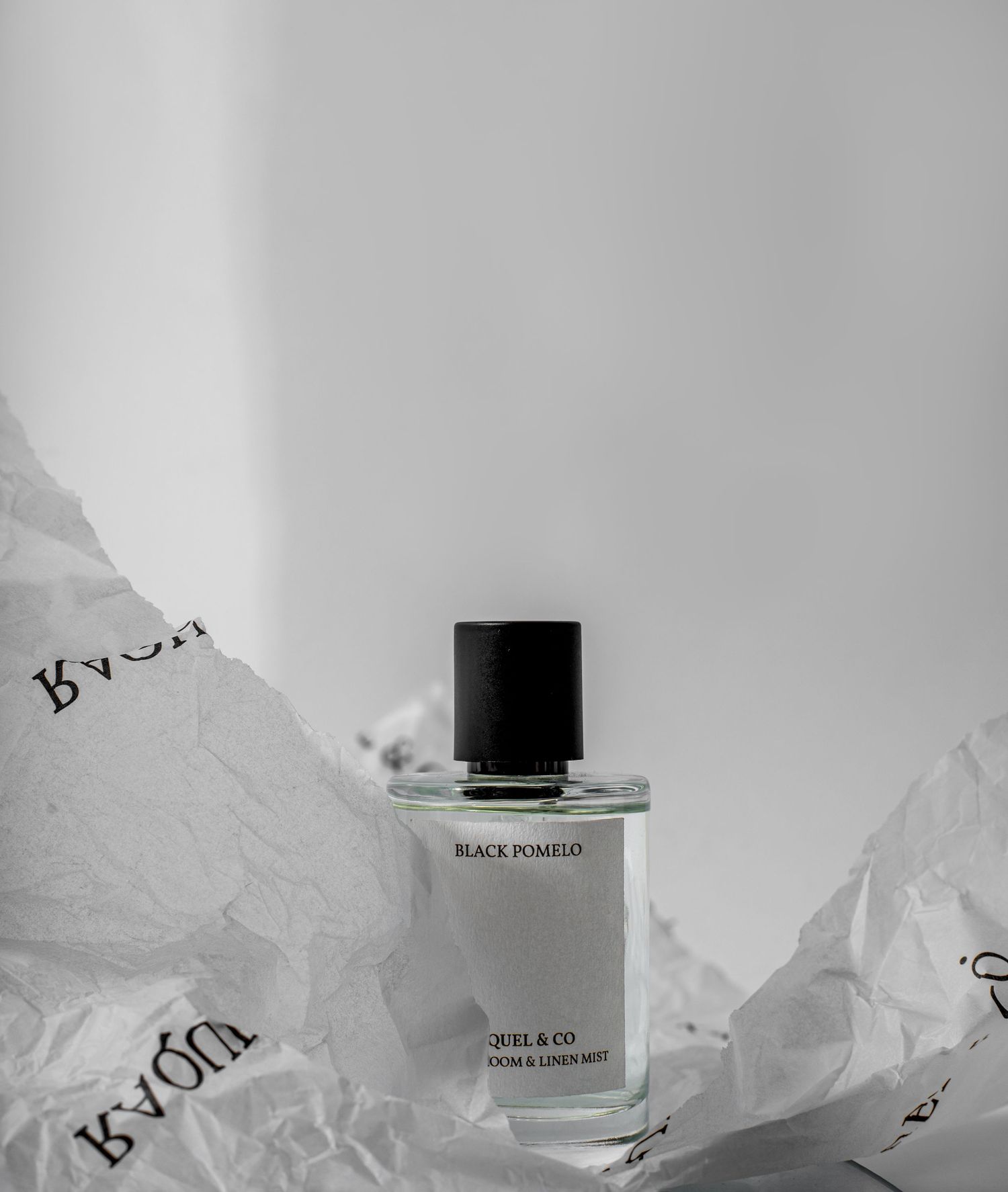 A bottle of Black Datura perfume displayed on crumpled white tissue paper against a light background.