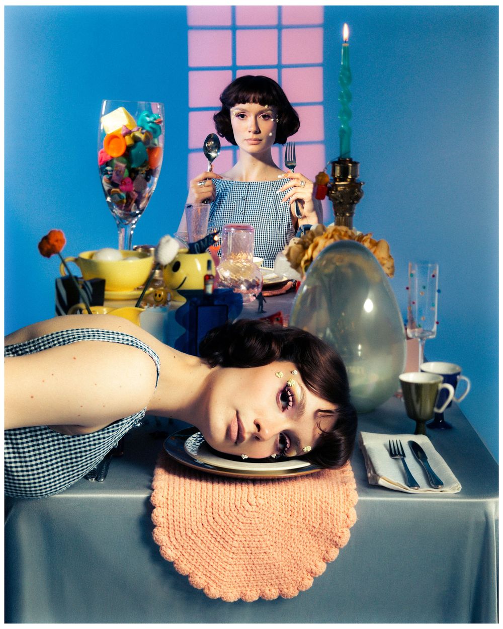 Surreal fine art photograph of a table setting with vintage decor, desserts and a head resting on a pink doily.