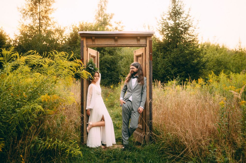 Rustic wooden archway framed by golden wildflowers and greenery at sunset.
