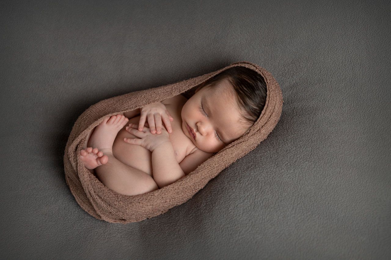 Newborn baby sleeping peacefully in a natural wrap at a Warkworth photography studio