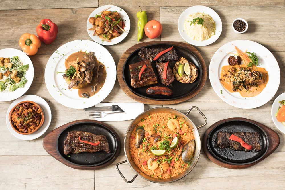 Overhead view of Korean BBQ feast with multiple meat dishes, sides and accompaniments.