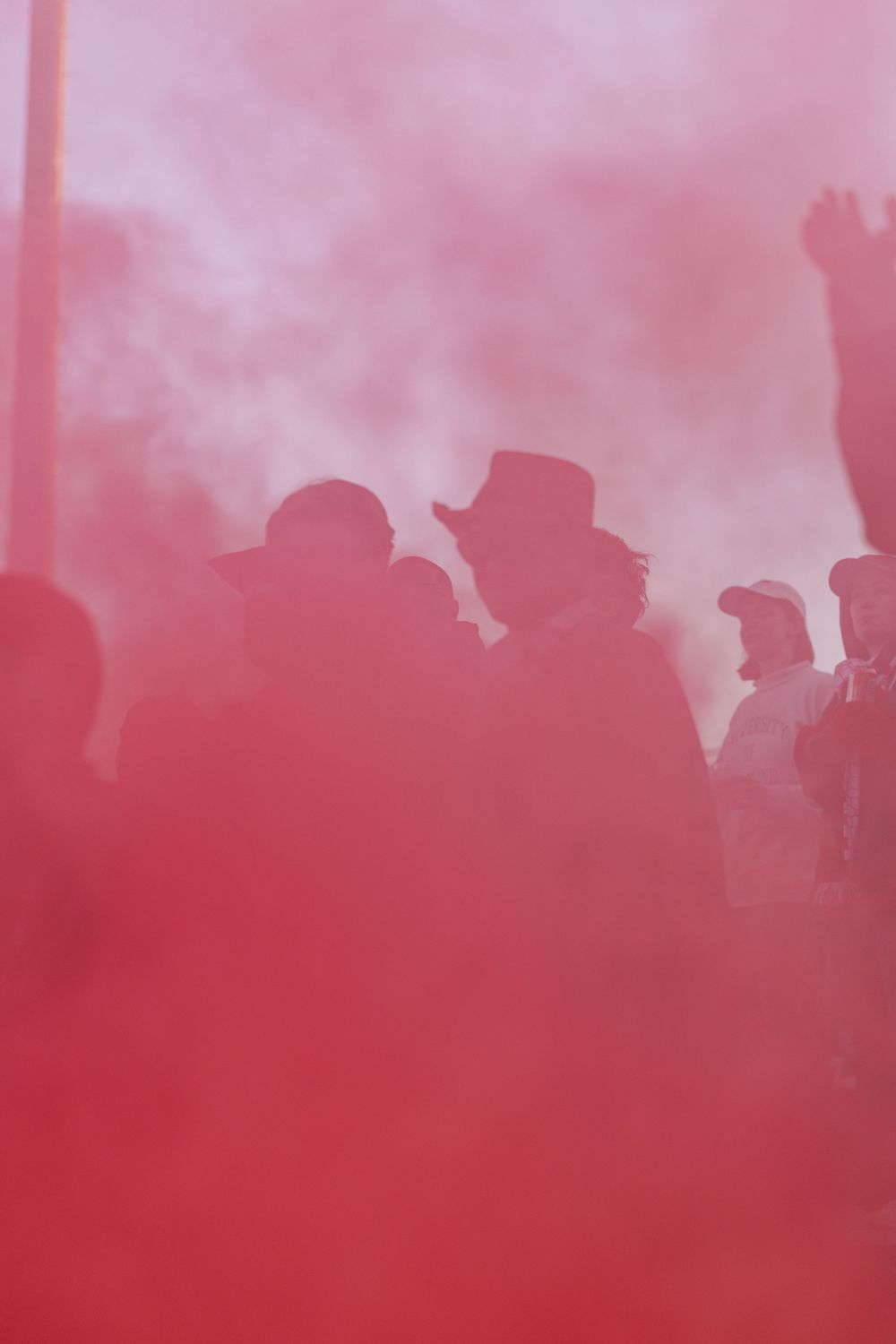 Red smoke fills the air at a crowded sporting event creating an atmospheric effect.