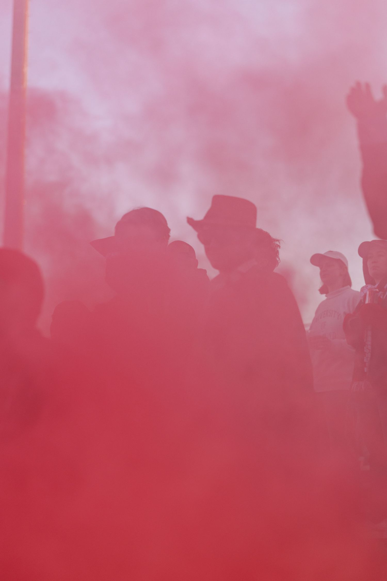Red smoke fills the air at a crowded sporting event creating an atmospheric effect.