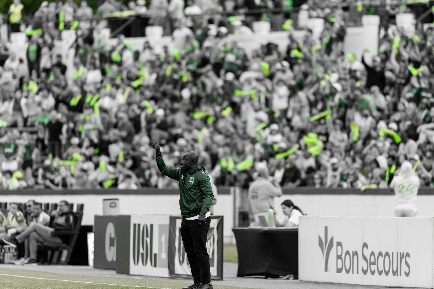 Black and white photo of a soccer stadium crowd with selective green coloring.