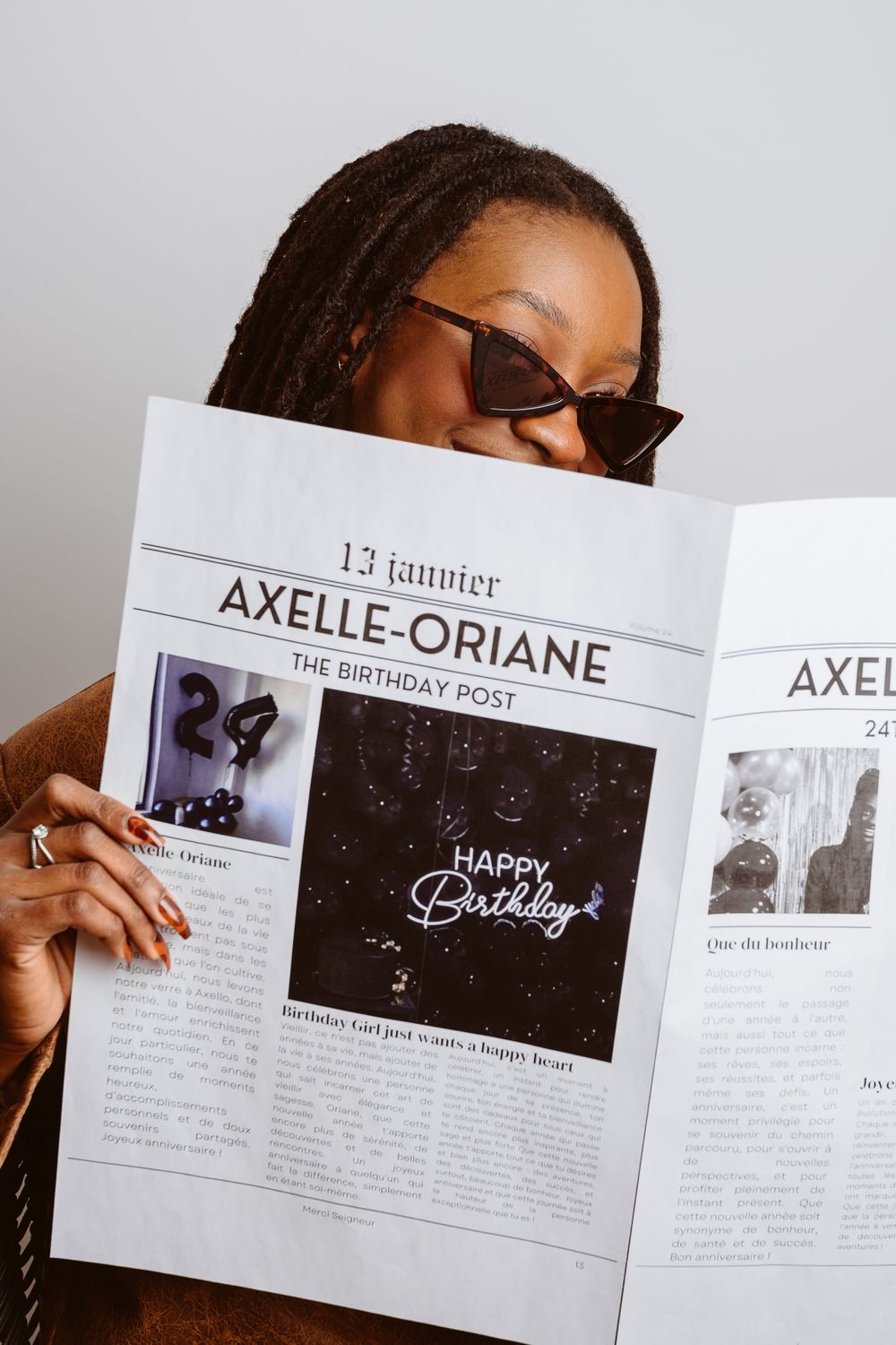 Person reading and holding birthday newspaper article spread with joyful expression.