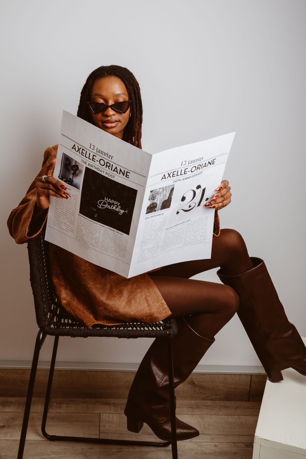 Person sitting casually in chair while reading a birthday newspaper feature.
