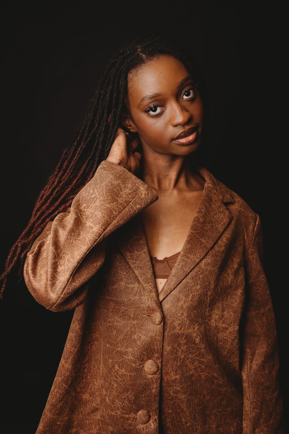 Fashion portrait series featuring textured brown coat against dark background.