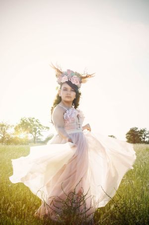 A child in a flowing pink dress twirls gracefully in a sunlit meadow during golden hour.