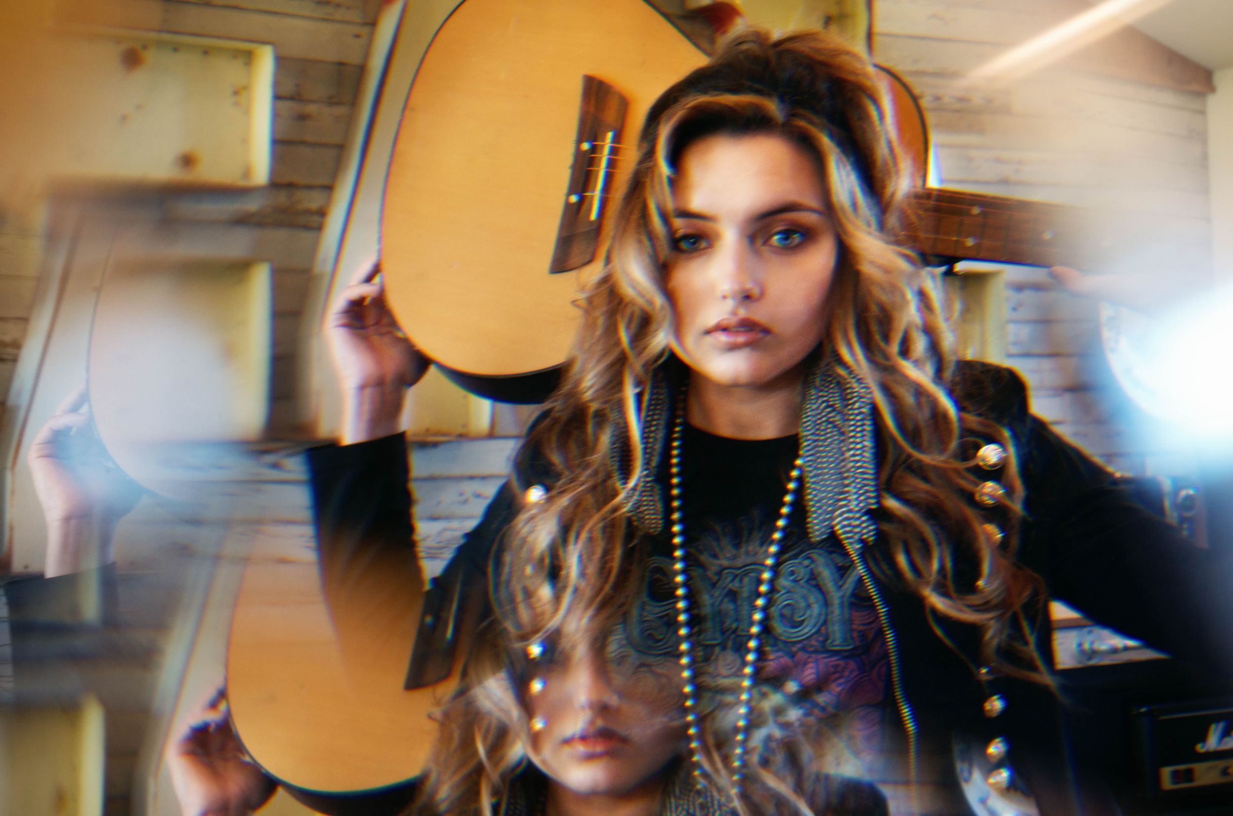 A teen girl stands with her guitar while wearing vintage clothing and a prism fractures the images with rainbows.