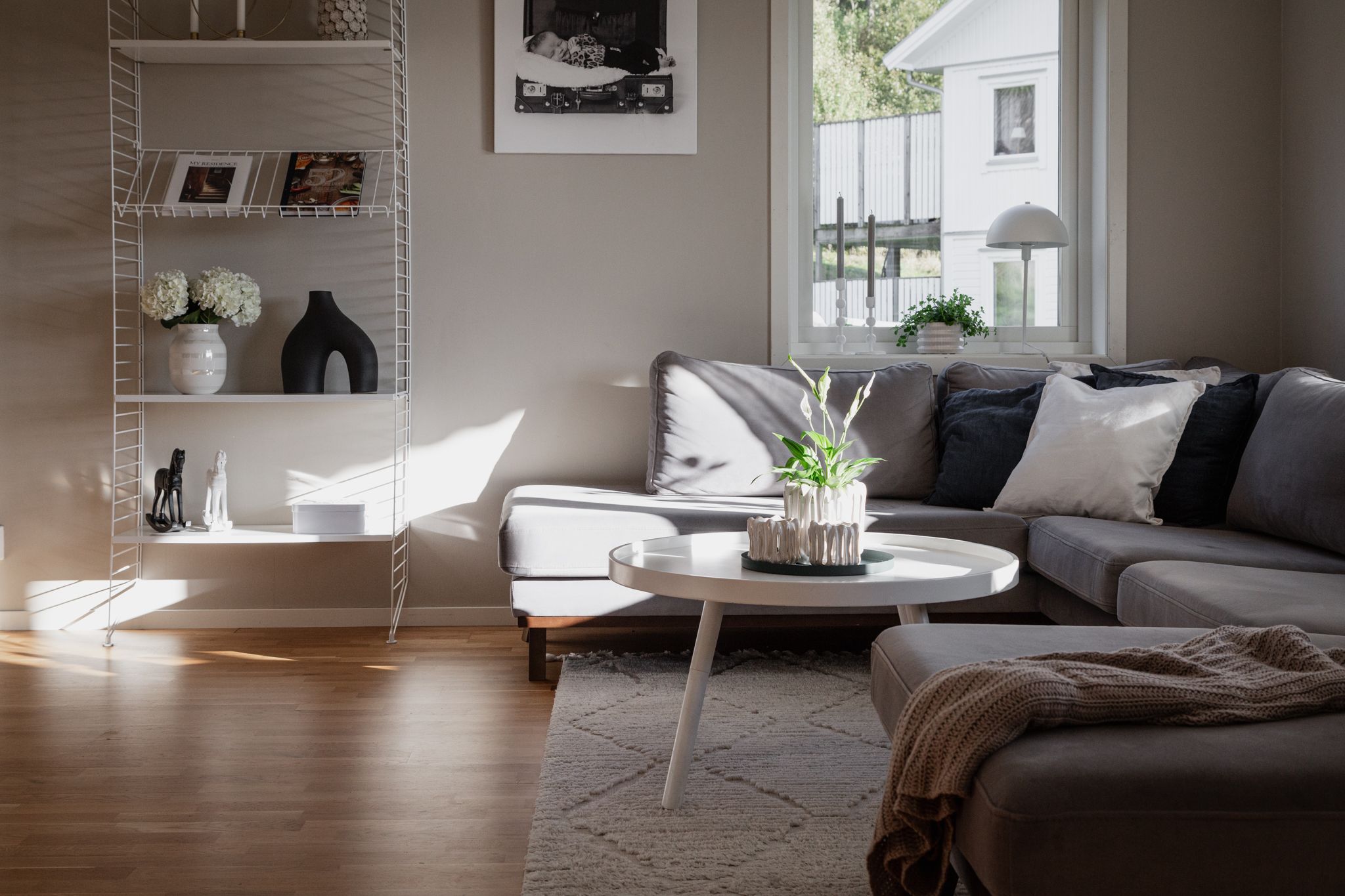 Modern Scandinavian living room with grey sectional sofa and round coffee table.