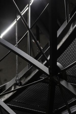 Abstract architectural detail of metal beams and lighting in dark industrial setting.