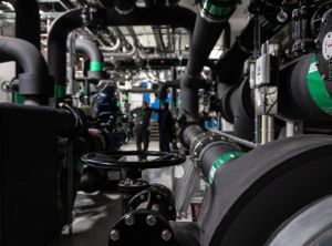 Industrial machinery and pipes in dimly lit factory interior.