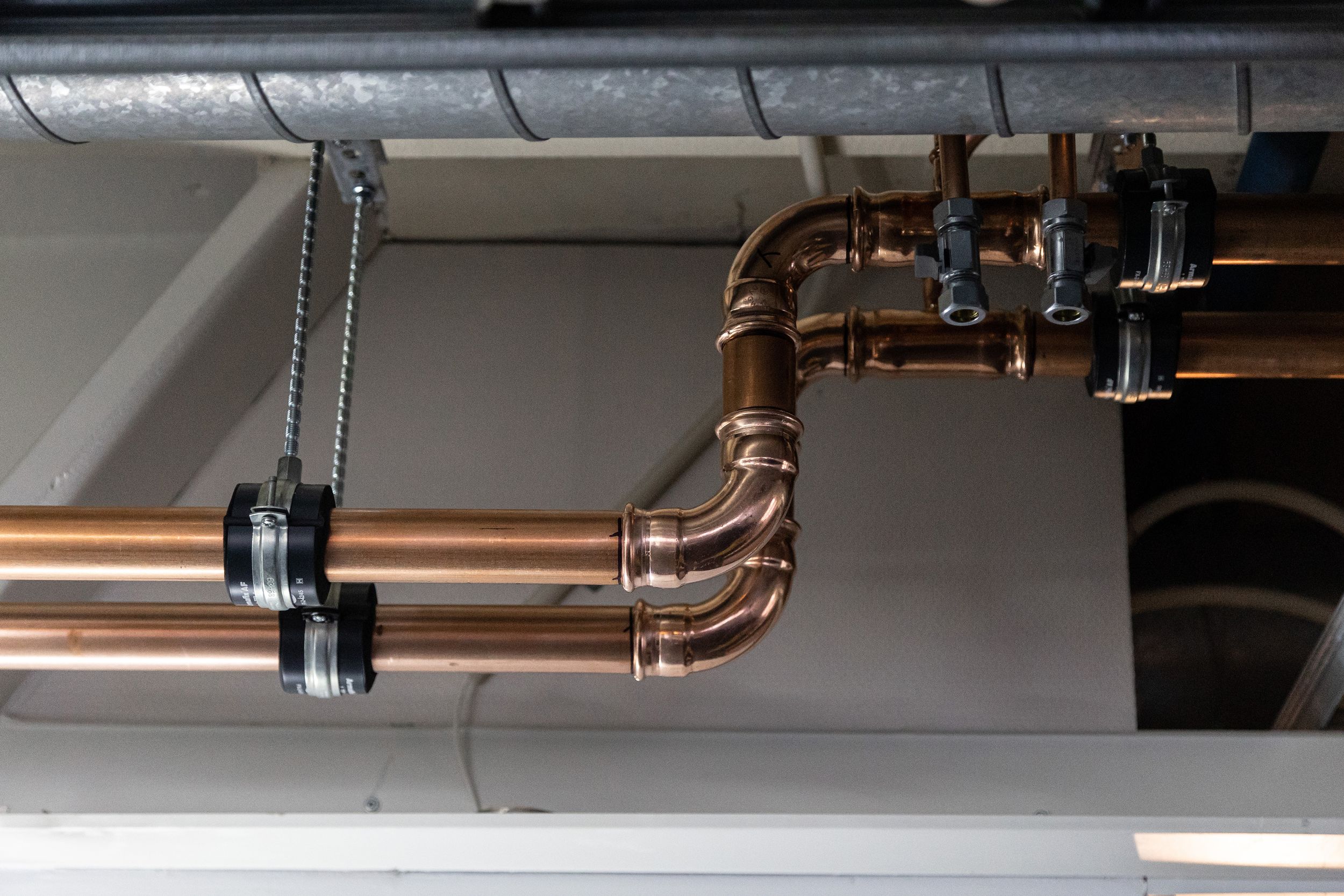 Copper plumbing pipes and fittings mounted on wall.