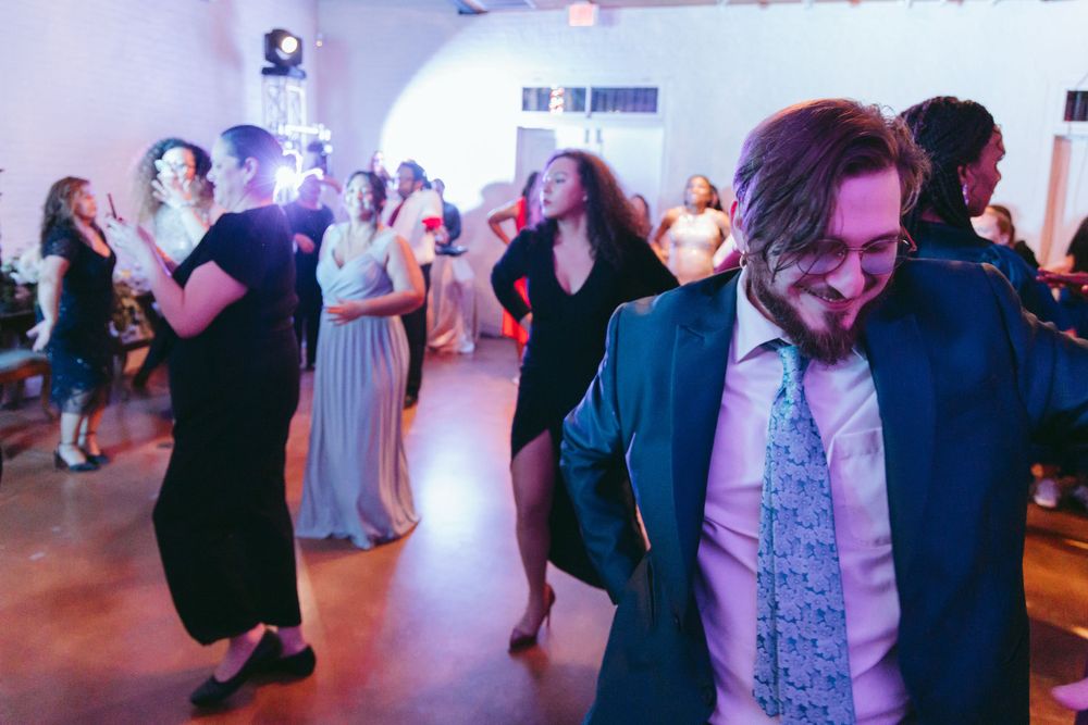 Wedding guests enjoying themselves on a lively dance floor with colorful lighting.