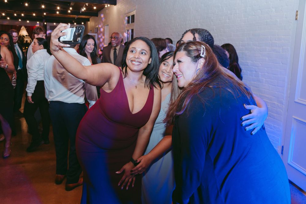 Party guests dancing and celebrating together under dim lighting at an indoor event.