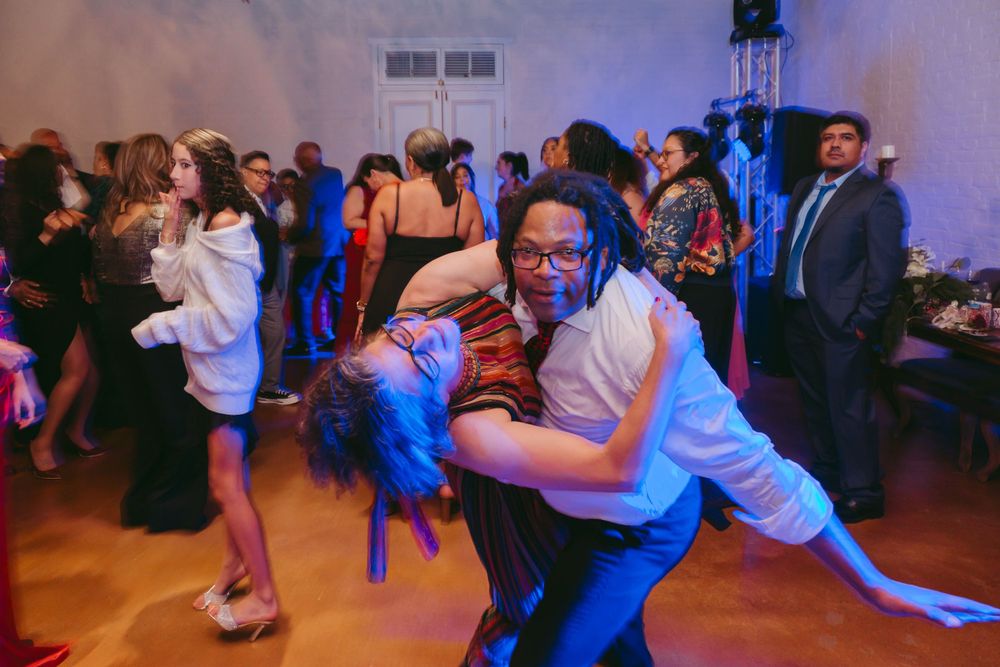 Couples dancing energetically on a dance floor with colorful lighting effects.