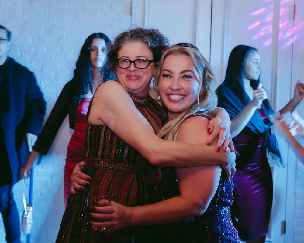 Party guests embracing and celebrating on a dance floor with blue lighting.