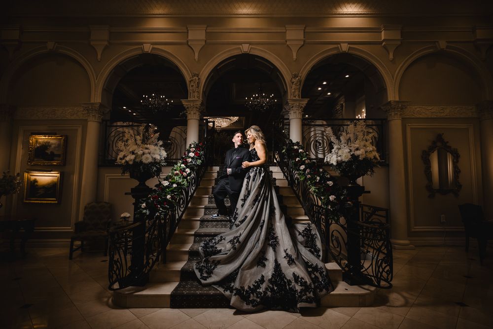 bride and groom in an intimate pose with her black lace dress drapped down the staircase at nanina's in the park