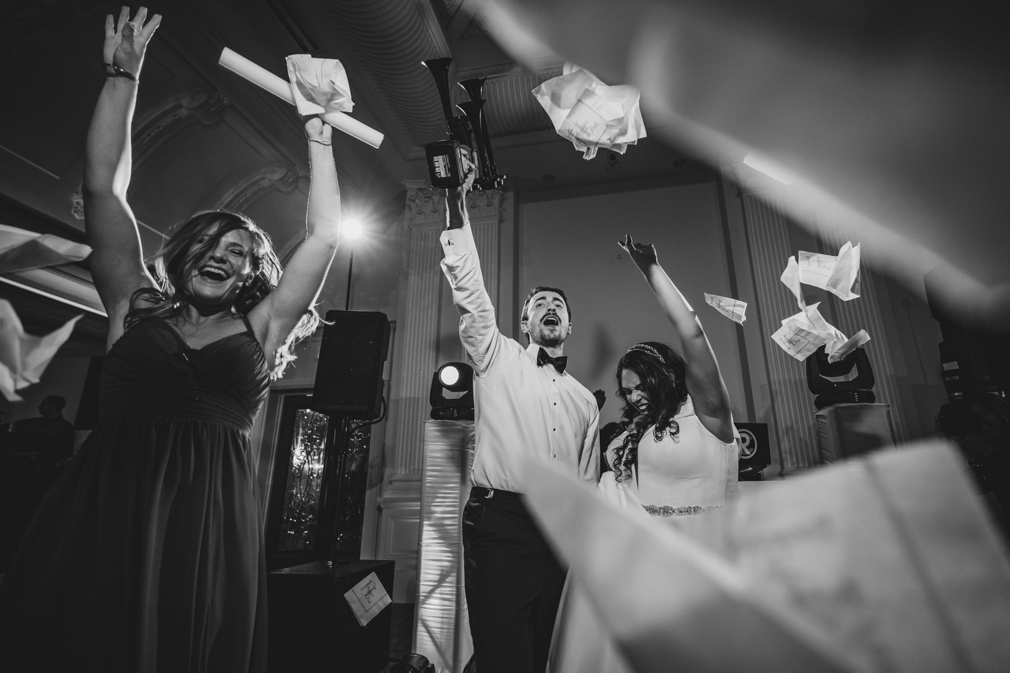 A dramatic black and white photo of bride and groom with raised arms dancing during their reception at nanina's in the park