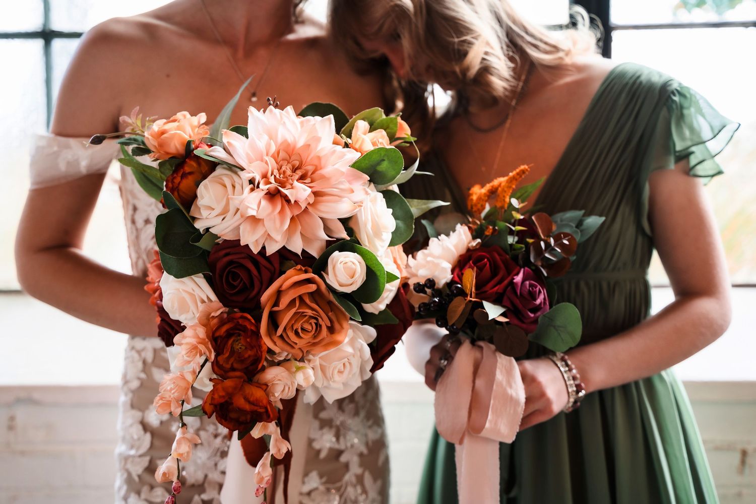 Bridesmaids hold elegant bouquets with coral dahlias, peach roses, and greenery in a romantic wedding setting.