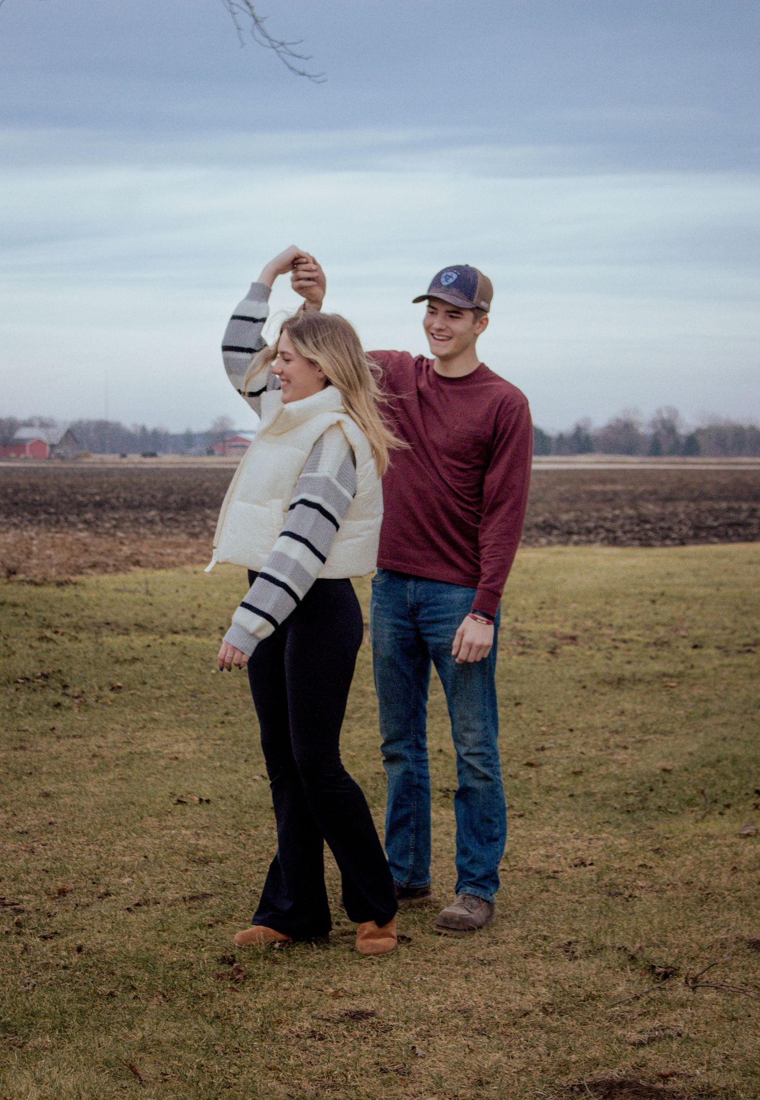 A young couple dances outdoors in a black and white photo, smiling joyfully in casual winter attire.