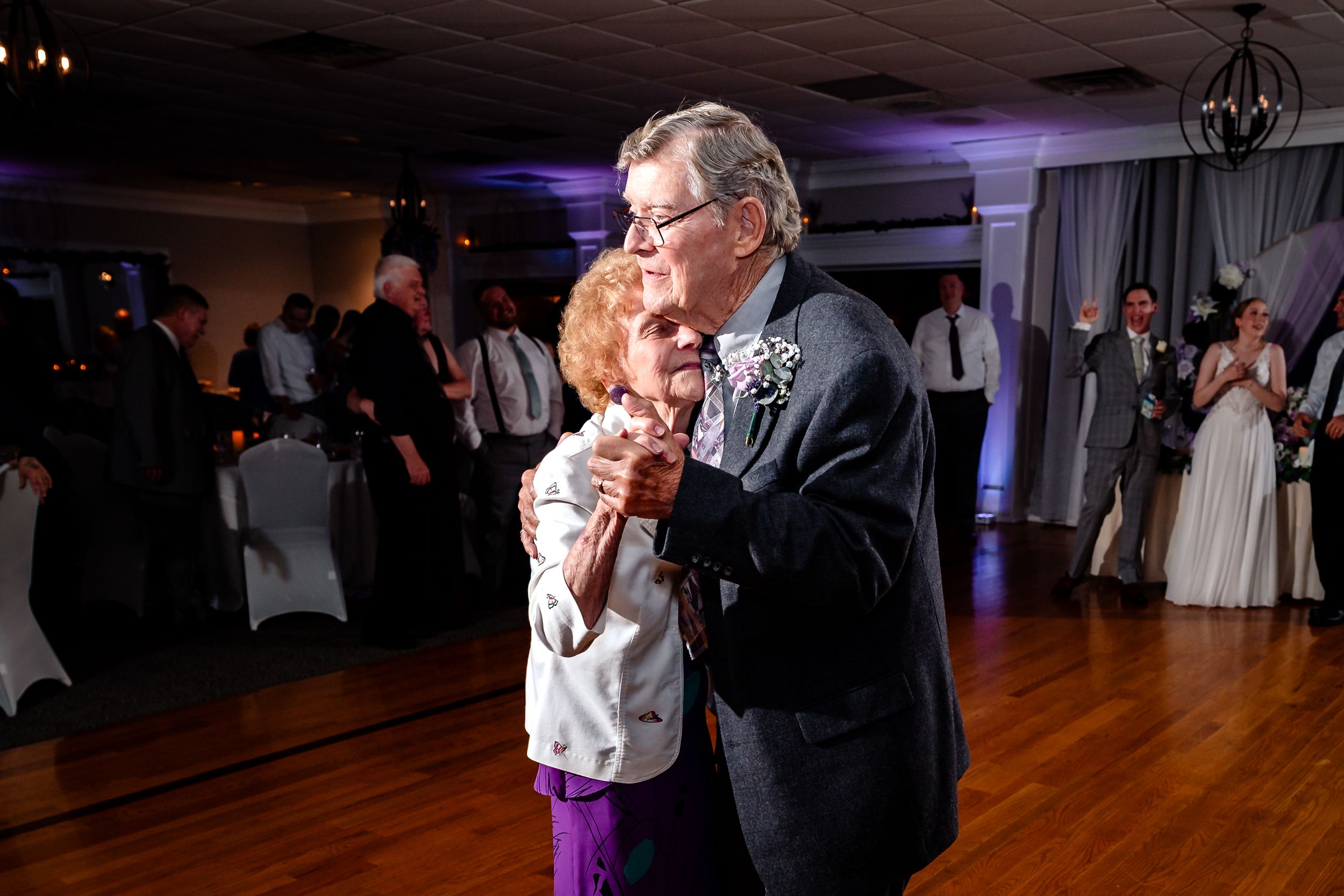Elderly couple shares a romantic slow dance together at a wedding reception.