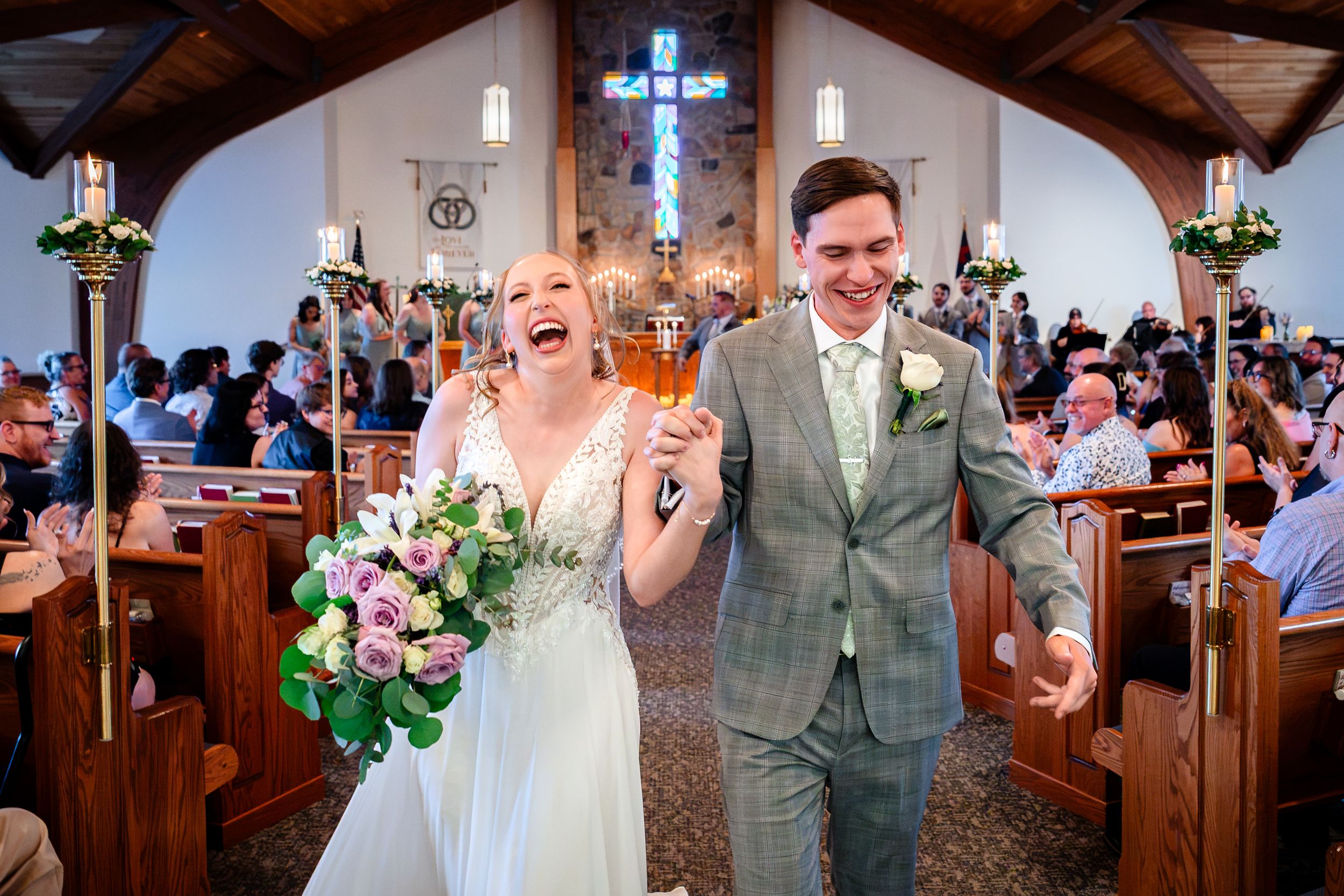A laughing bride and groom walk back down the aisle after their church wedding ceremony.