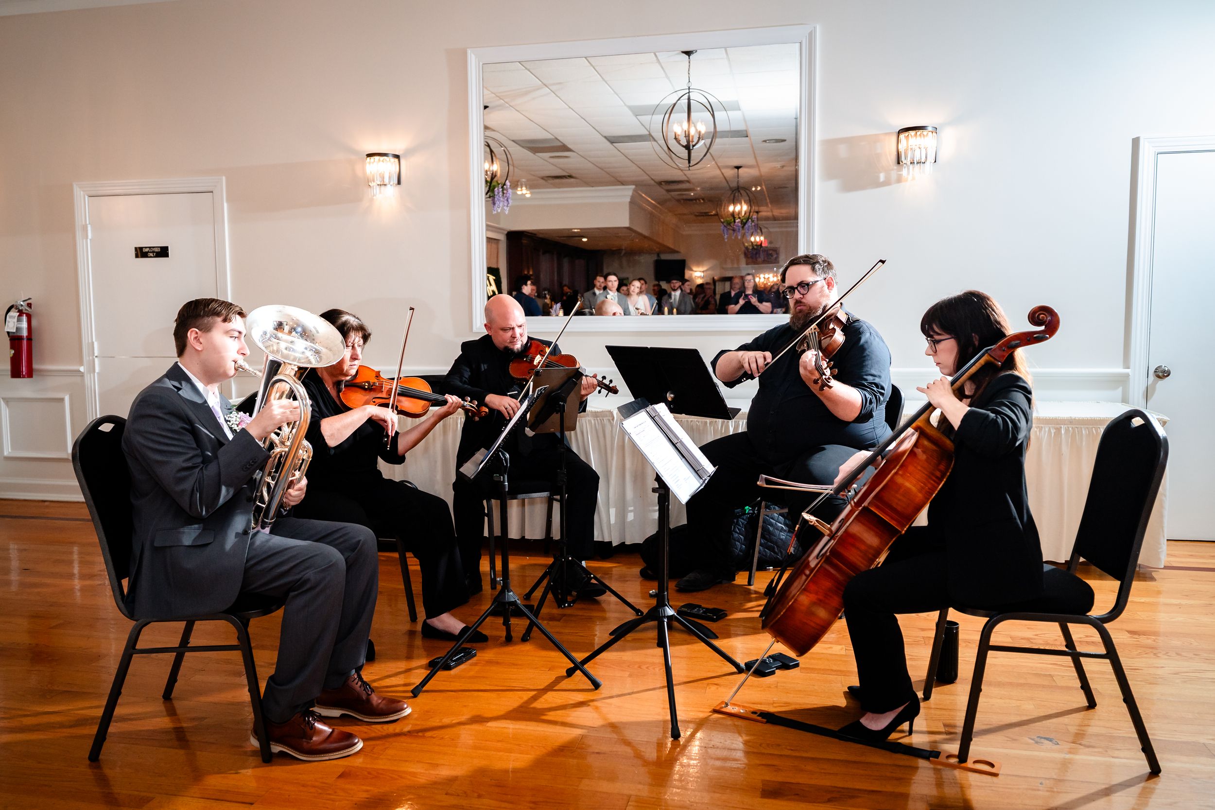 String quartet performing at an elegant indoor wedding reception venue with chandelier lighting.