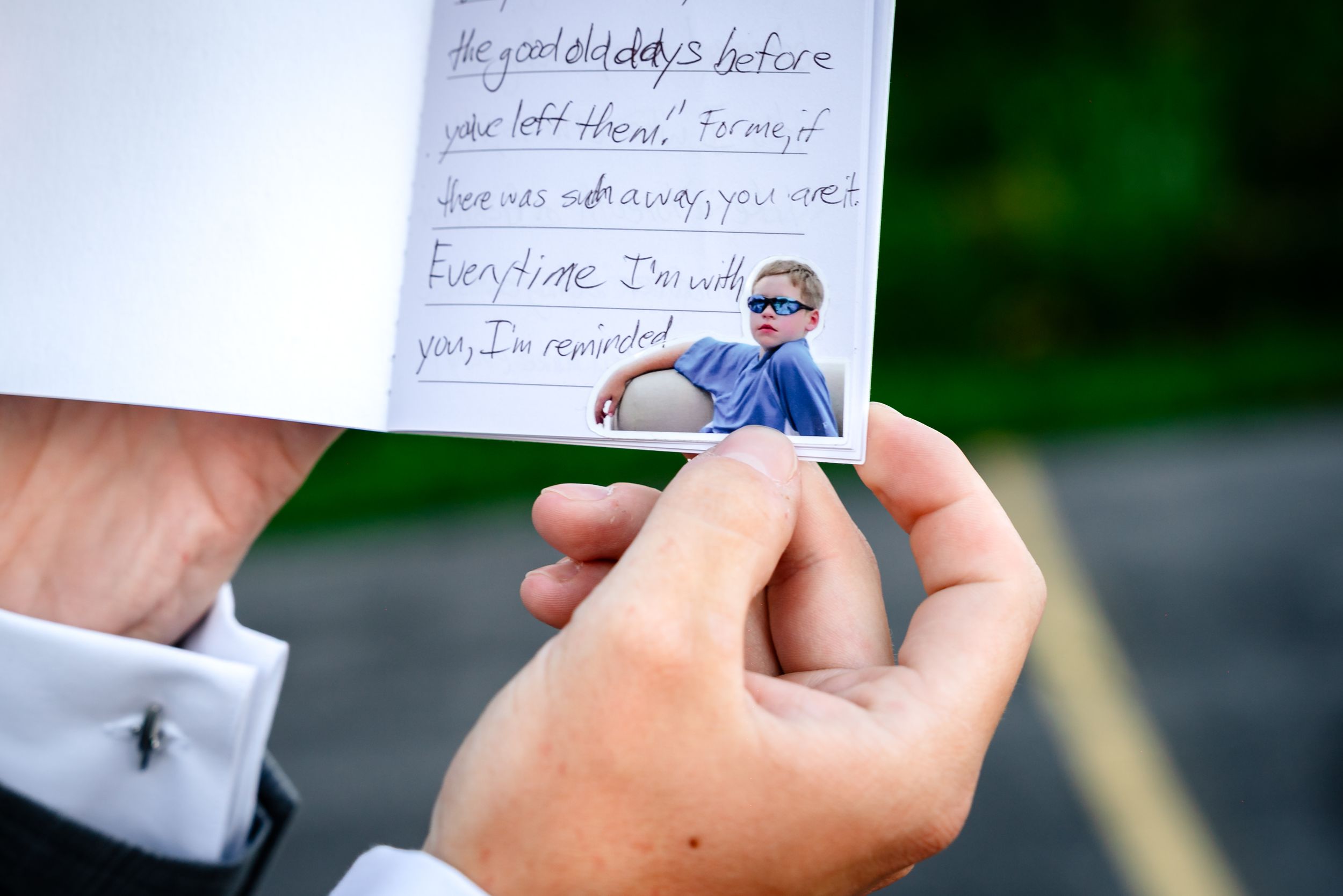 Person holding a handwritten letter with a photo of a young boy wearing sunglasses attached to the card.