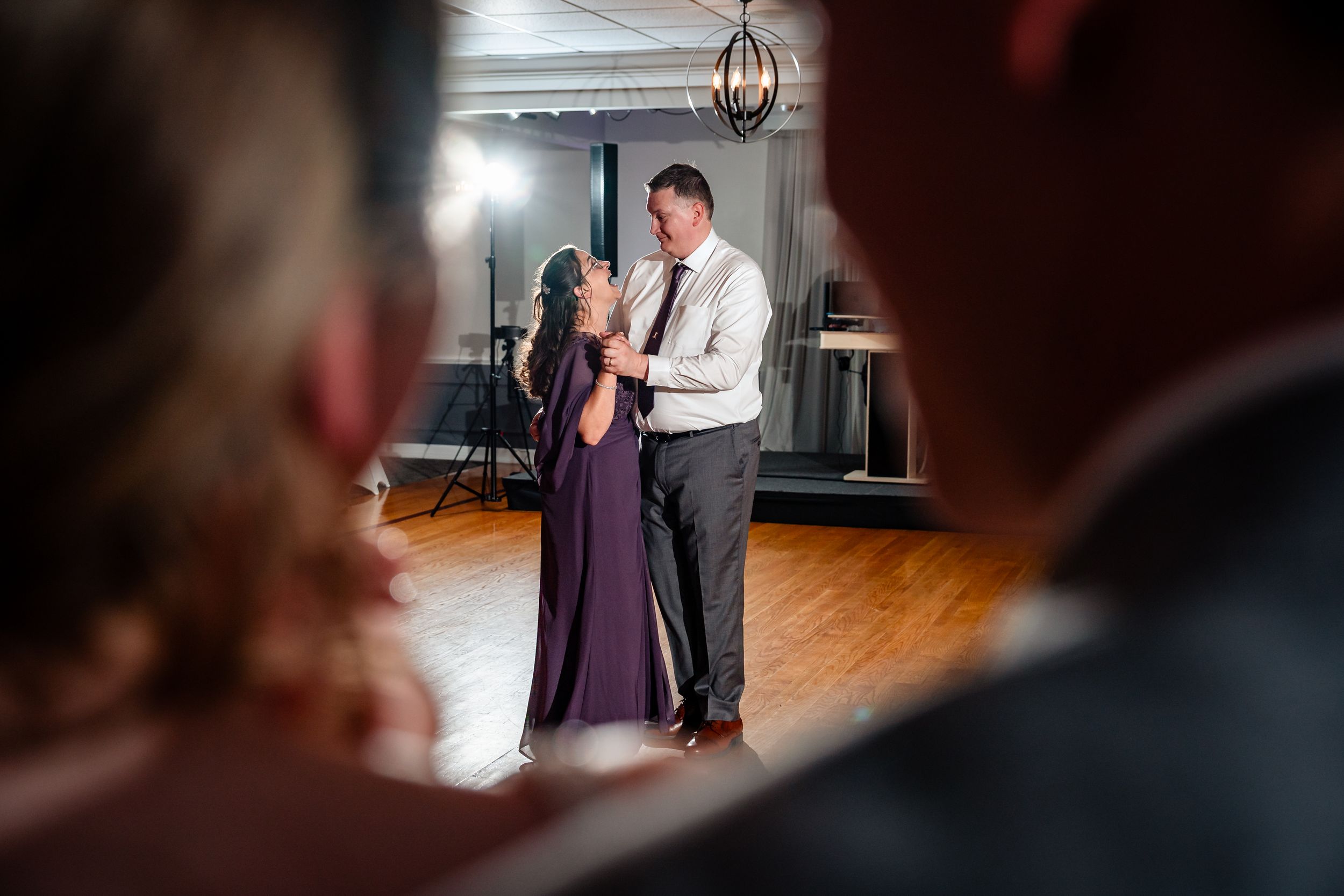 Couple sharing a romantic first dance at a wedding reception on a wooden dance floor.
