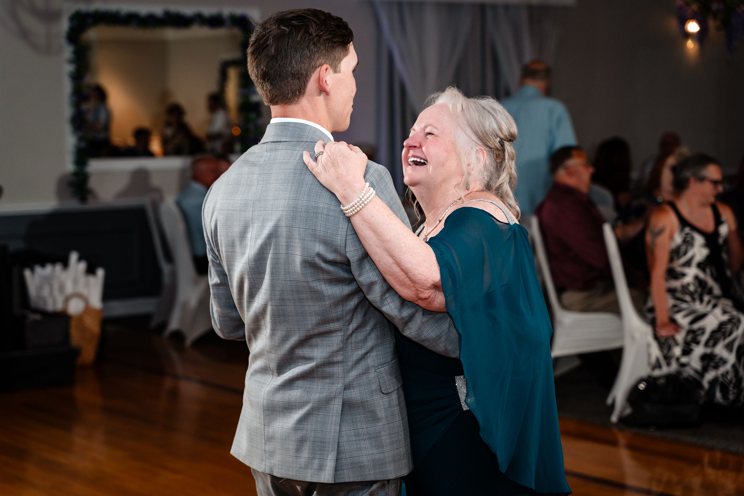 Groom shares a joyful mother-son dance at elegant wedding reception indoor venue.