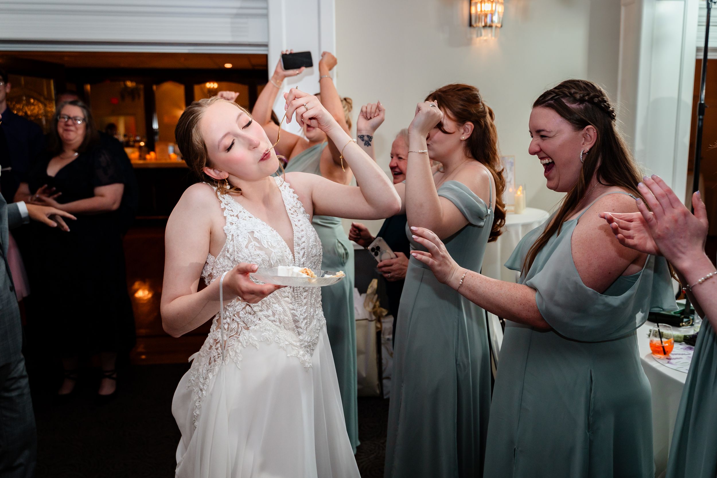 Bride dancing joyfully with bridesmaids in sage green dresses at a wedding reception celebration.