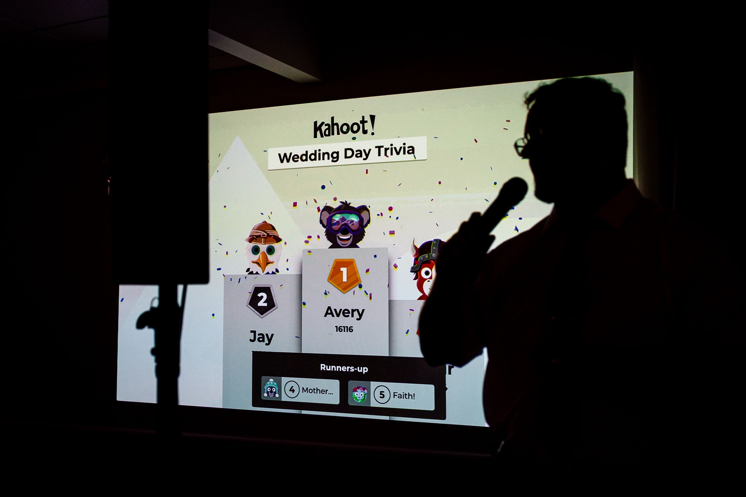 Silhouetted guests play Kahoot Wedding Day Trivia game projected on screen showing leaderboard with Avery in first place.