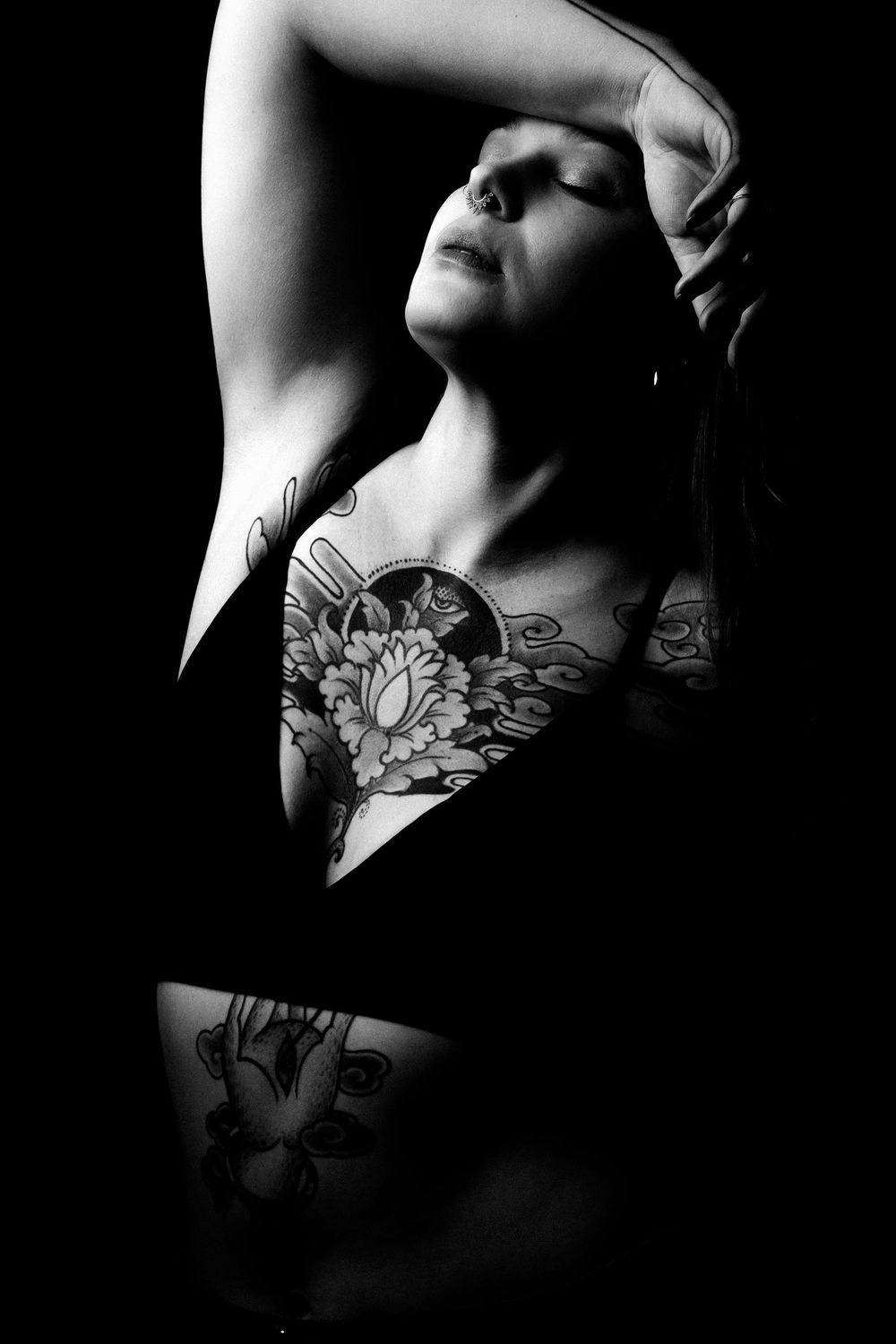 Portrait artistique en noir et blanc d'une femme tatouée réalisé en clair-obscur.