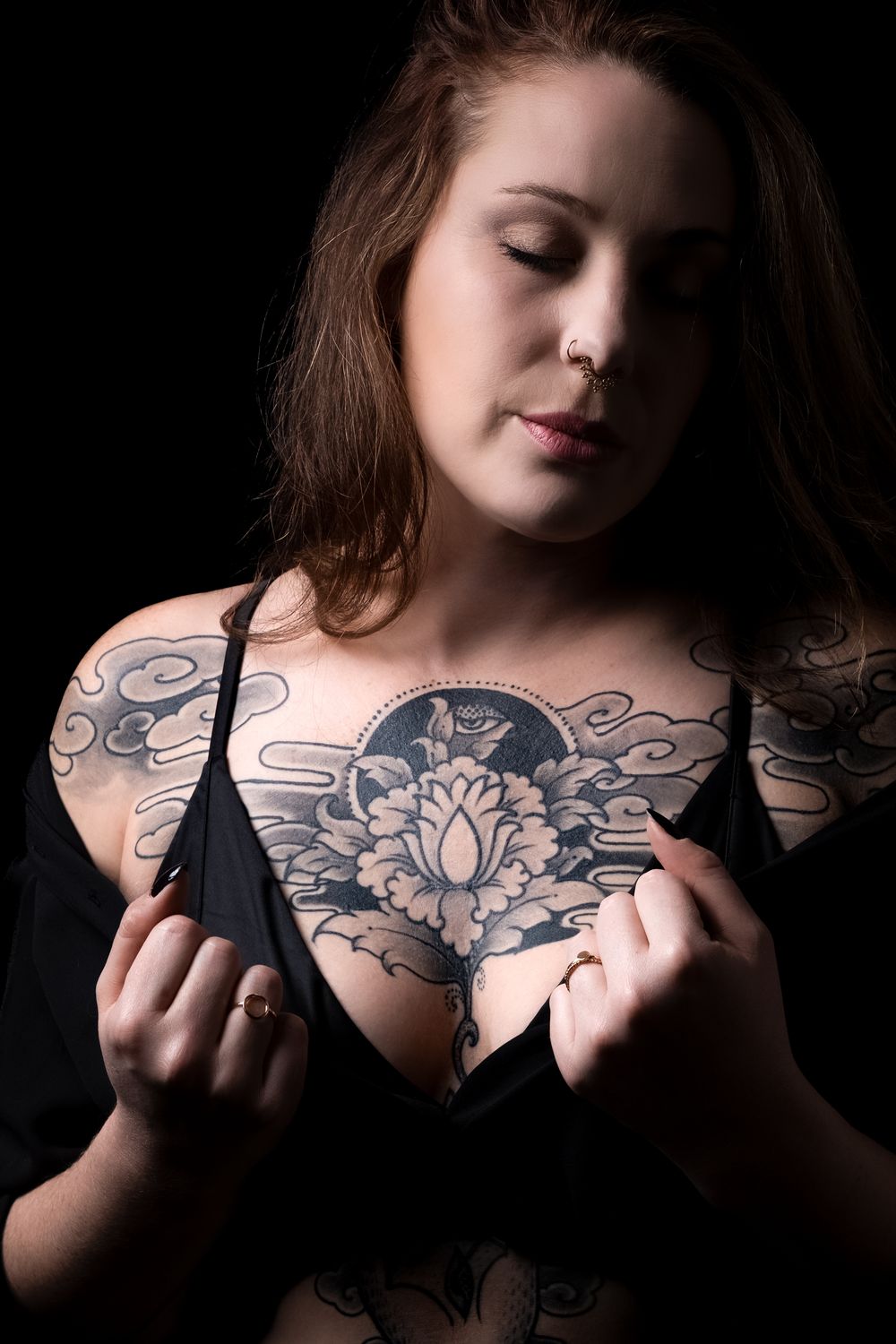 Portrait intimiste en studio d'une femme tatouée réalisé sur fond noir.