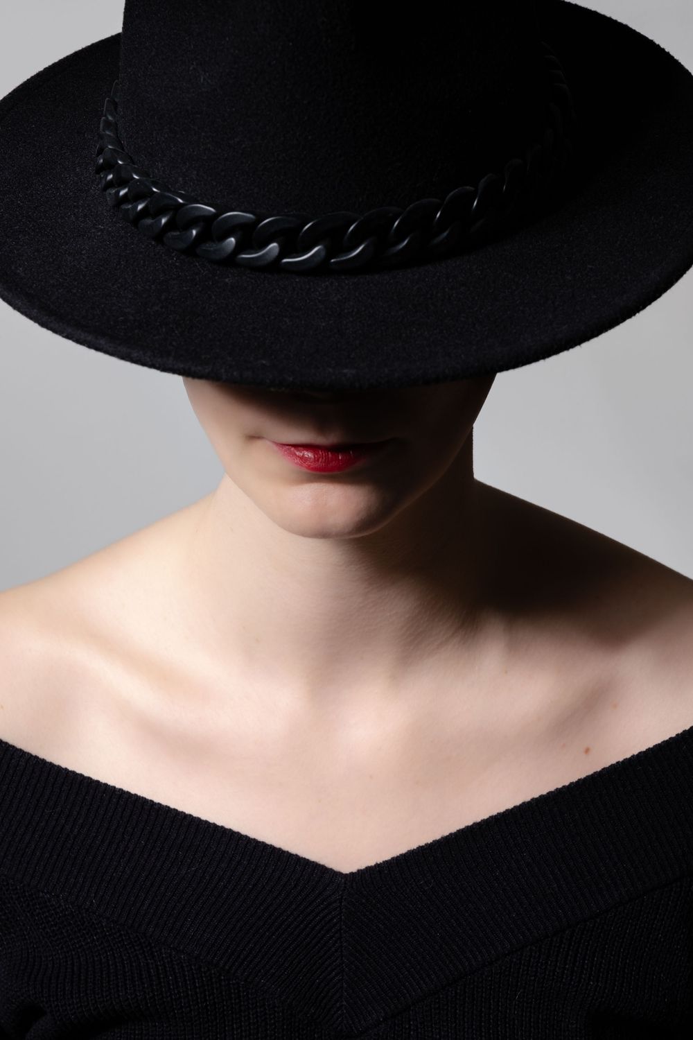 Portrait féminin en studio avec chapeau noir et rouge à lèvres rouge.