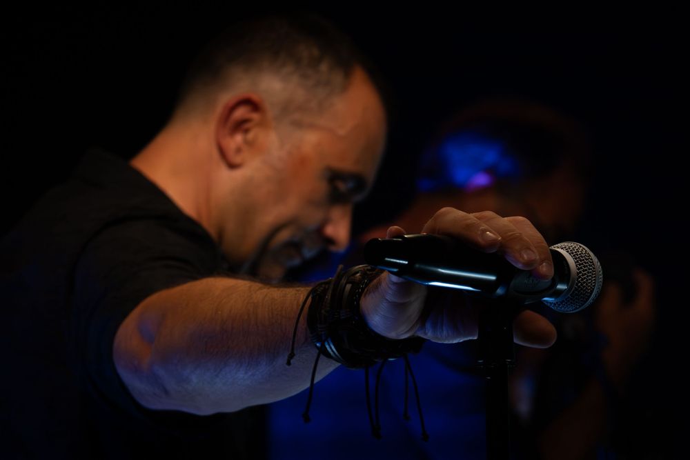 Chanteur tenant un micro sous un éclairage de scène pendant un concert.