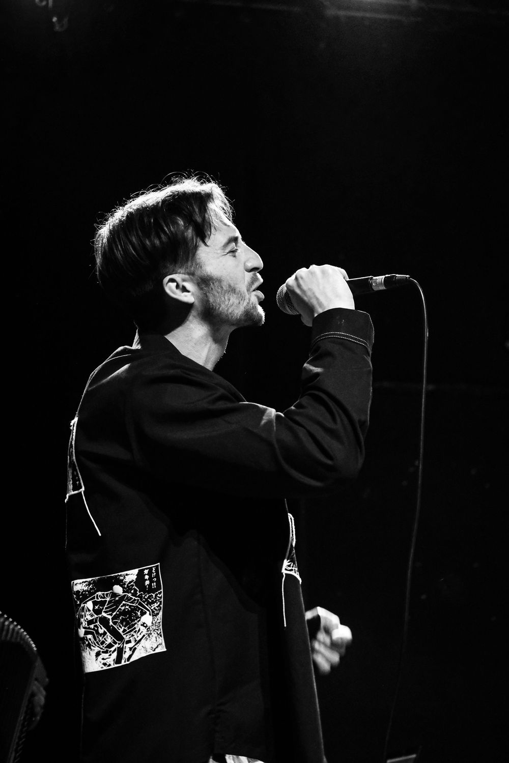 Chanteur interprétant un morceau sur scène lors d'un concert live en noir et blanc.