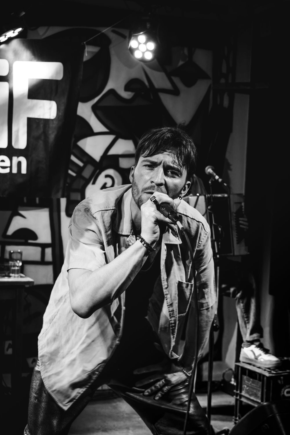 Chanteur interprétant un morceau sur scène lors d'un concert en noir et blanc.
